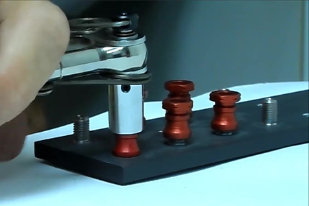 A technician using a tool to install a hi-lok aerospace fastener into a structural component of an aircraft wing