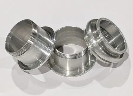 Batch production of high-speed CNC turned concentric aluminum components displaying tight-tolerance bored features and mirror-like surface finishes. 